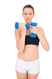 Serious sporty brunette working out with dumbbells