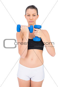 Serious sporty brunette working out with dumbbells