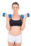 Focused sporty brunette working out with dumbbells