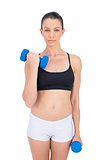 Peaceful sporty brunette working out with dumbbells