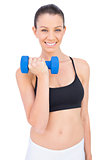 Cheerful woman lifting dumbbell