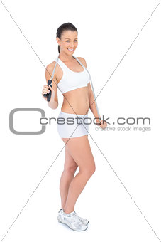 Cheerful woman holding skipping rope and smiling at camera