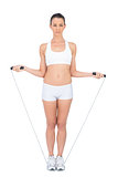 Serious woman in sportswear exercising with skipping rope