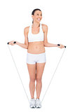 Smiling woman in sportswear exercising with skipping rope