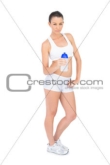 Serious pretty woman in sportswear holding flask