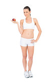 Portrait of woman in sportswear holding red apple