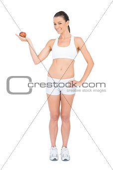 Smiling woman holding red apple looking at camera