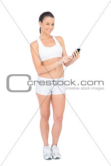 Happy woman in sportswear using phone smiling at camera