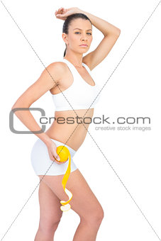 Portrait of fit woman in sportswear holding orange by her thigh