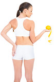 Woman in sportswear standing back to camera holding orange