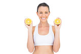 Smiling woman holding slices of orange looking at camera