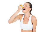 Smiling sporty woman drinking juice from orange
