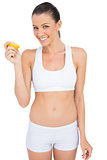 Smiling woman in sportswear holding slice of orange looking at camera