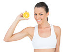 Happy woman in sportswear holding slice of orange