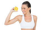 Smiling woman in sportswear holding orange slice