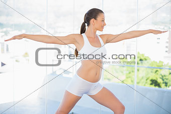 Smiling fit woman stretching in yoga warrior pose