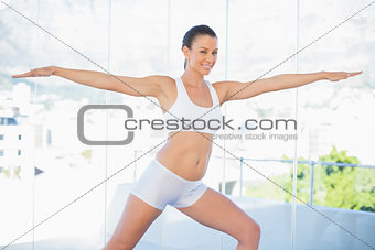 Cheerful fit woman stretching in yoga warrior pose