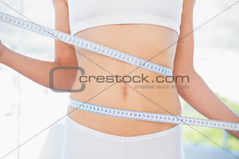 Mid section of woman measuring her waist