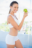 Fit smiling woman holding green apple