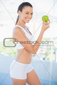 Fit smiling woman holding green apple