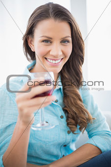 Cheerful gorgeous brunette holding glass of red wine