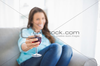 Cheerful gorgeous woman offering glass of red wine