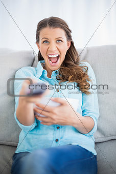 Woman sitting on sofa screaming while watching tv