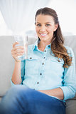 Gorgeous casual woman on couch holding glass of water