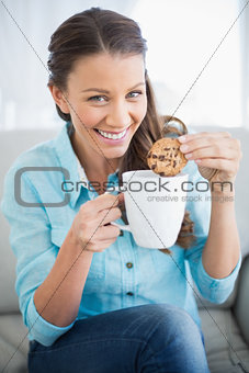Smiling woman dunking cookie in coffee