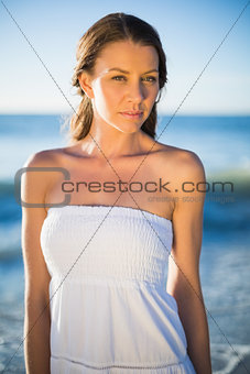 Serious brunette in white summer dress posing