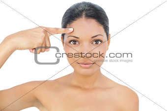 Gorgeous black haired model pointing at her forehead