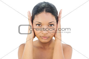 Serious black haired model blocking her ears