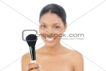 Smiling black haired model holding blusher brush