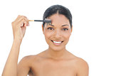 Smiling black haired model using eyebrow brush
