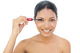 Cheerful black haired model applying mascara
