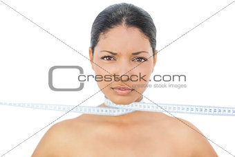 Cheerful black haired model strangling herself with measuring tape