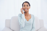 Cheerful attractive woman on the phone sitting on cosy sofa
