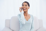 Smiling attractive woman on the phone sitting on cosy sofa