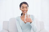 Smiling attractive woman sitting on cosy sofa drinking water
