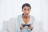 Shocked woman sitting on sofa playing video games