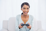 Smiling woman sitting on sofa playing video games