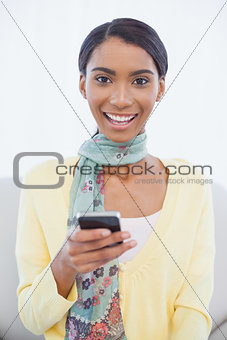 Smiling pretty woman sitting on sofa text messaging