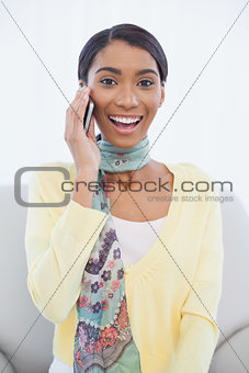 Smiling pretty woman sitting on sofa having a phone call