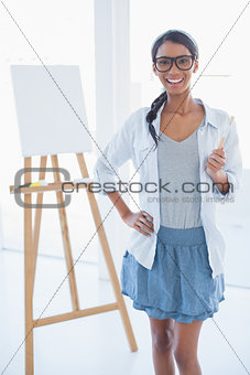 Smiling attractive artist holding paintbrush