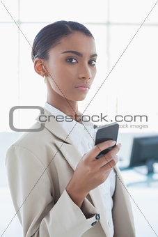 Stern elegant businesswoman text messaging