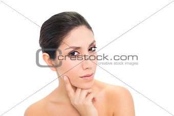 Thoughtful brunette with finger on her face looking at camera