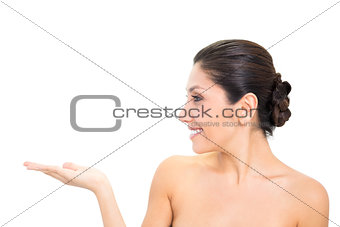 Smiling brunette presenting with hand with head turned
