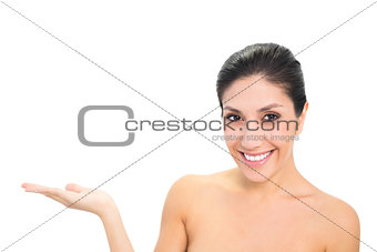 Smiling brunette presenting with hand looking at camera