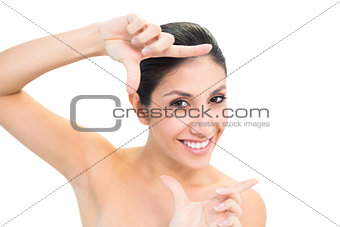 Smiling brunette looking at camera framing her face with hands