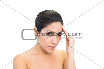 Frowning brunette with a headache looking at camera